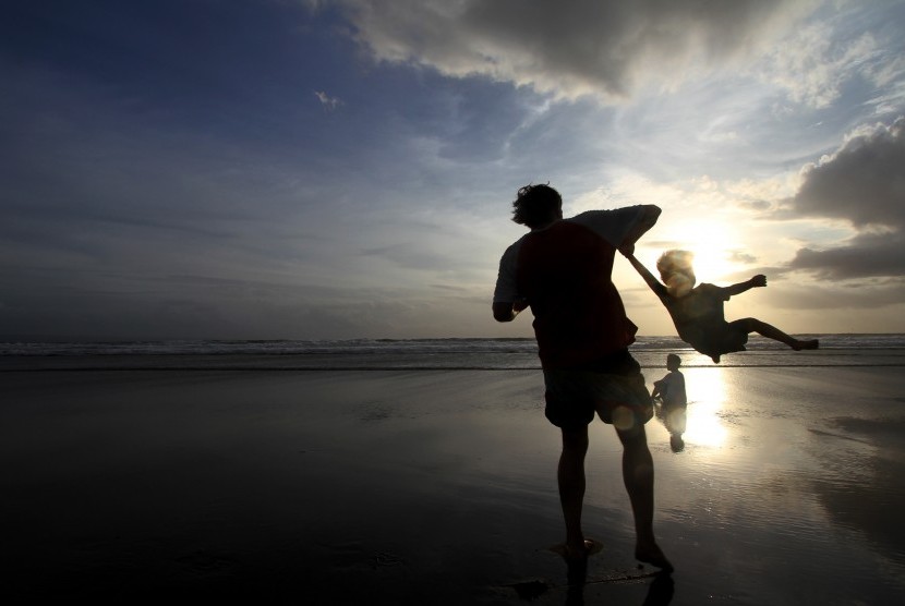 Wisatawan mancanegara bermain bersama anaknya di pantai Seminyak, Bali.