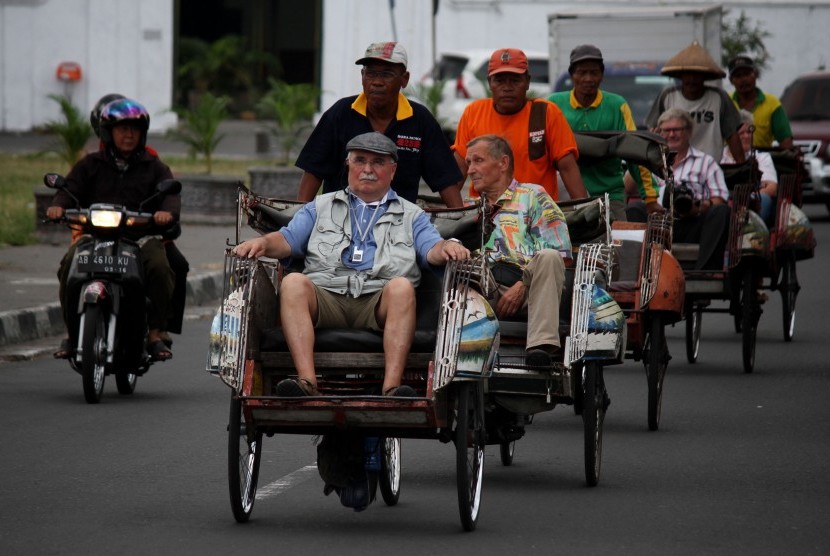 Wisatawan mancanegara (wisman) naik becak berkeliling kota saat melintas di Alun-Alun Selatan, Yogyakarta, Kamis (24/7). 