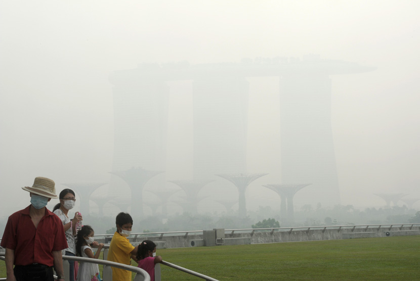  Wisatawan memakai masker saat berwisata melihat Marina Bay Sands Casino dan Supertree grove yang terselubung kabut asap di Singapura, Kamis (20/6).   (AP/Joseph Nair)