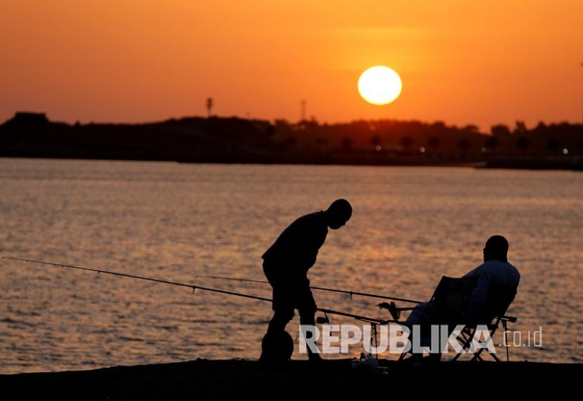  Pulau Farasan Saudi Rayakan Musim Memancing Tahunan. Foto:   Wisatawan memancing saat matahari terbenam di pantai Laut Merah, di Jiddah, Arab Saudi, Kamis, 9 Juli 2020. 