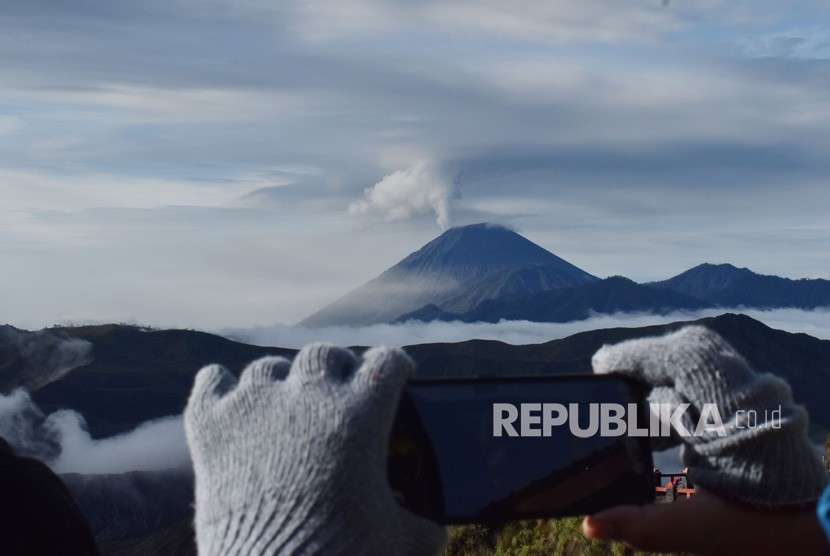 Wisatawan memotret Gunung Semeru yang menyemburkan awan panas, dari Pananjakan Pasuruan, Jawa Timur, Sabtu (7/3/2020).