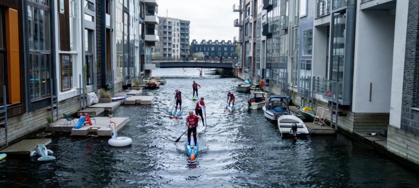 Wisatawan menaiki paddleboard untuk menyusuri kanal di Copenhagen, Denmark. 