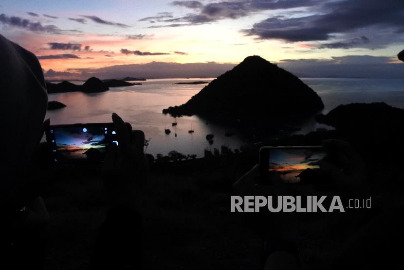 Wisatawan mengabadikan suasanai matahari terbenam (sunset) di kawasan wisata Bukit Silvia, Labuan Bajo, Manggarai Barat, NTT Minggu (19/1).