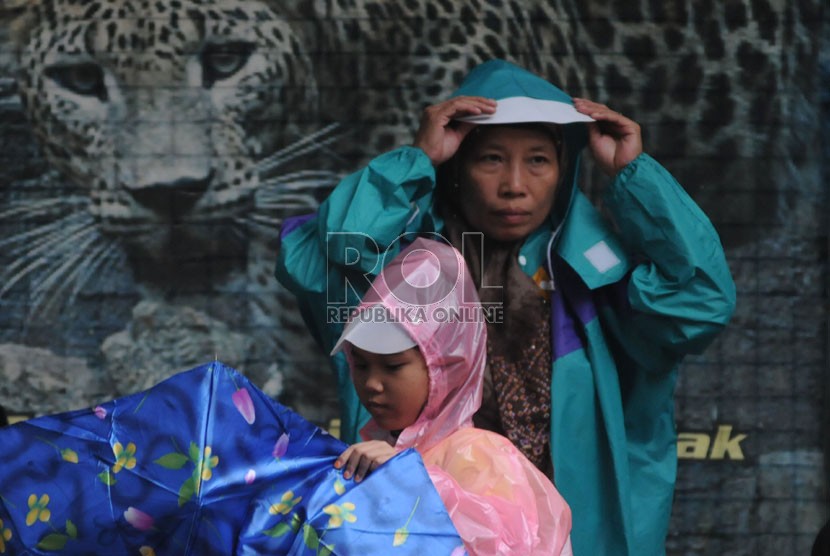   Wisatawan mengenakan jas hujan saat hujan turun di Kebun Binatang Ragunan,Jakarta,Selasa (25/12). (Republika/Aditya Pradana Putra)