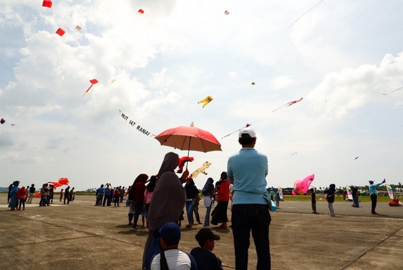 Wisatawan menikmati layang-layang yang diterbangkan di ajang Festival Layang-Layang Internasional 2018 di Ranai, Kabupaten Natuna, Kepulauan Riau