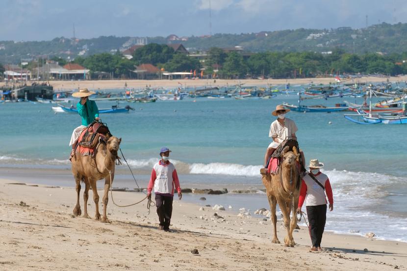 Wisatawan menikmati suasana pantai dengan menaiki unta saat liburan di Pantai Kelan, Badung, Bali. Ada beberapa keuntungan menyewa mobil sendiri saat liburan di Bali.