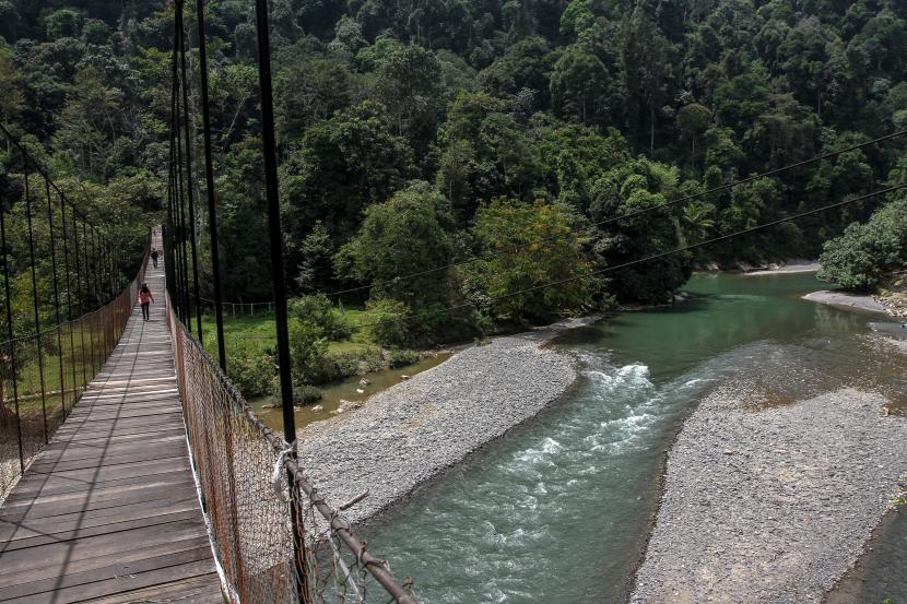 Wisatawan menyeberangi jembatan gantung di Kawasan Hutan Wisata Taman Nasional Gunung Leuser (TNGL) Tangkahan, Kabupaten Langkat, Sumatera Utara, Kamis (4/2/2021). TNGL Tangkahan melatih Gajah Sumatera untuk menjadi salah satu daya tarik wisata di kawasan tersebut.
