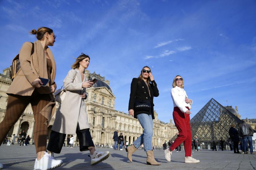 Wisatawan tanpa masker berjalan di area Louvre Museum di Paris, Prancis, Senin (14/3/2022). WHO mengatakan, sejumlah negara Eropa, termasuk Jerman, Prancis, Italia, dan Inggris, mencabut pembatasan sosial Covid-19 dengan terlalu “brutal”.