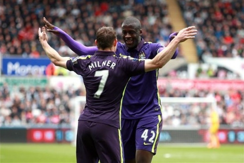 Yaya Toure (kanan) berpelukan dengan James MIlner