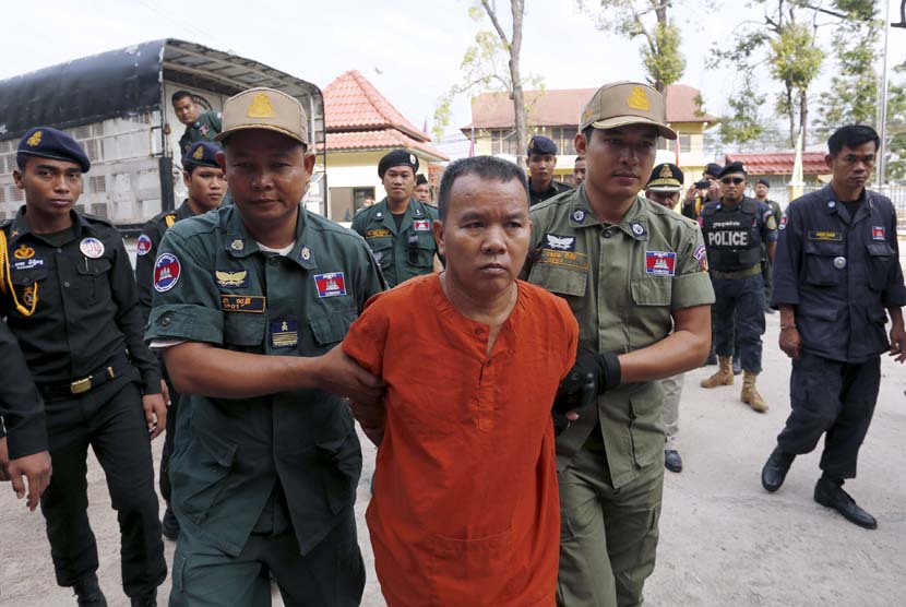 Yem Chrin (tengah) digiring aparat kepolisian saat tiba di pengadilan Battambang, Kamboja, Kamis (3/12). 
