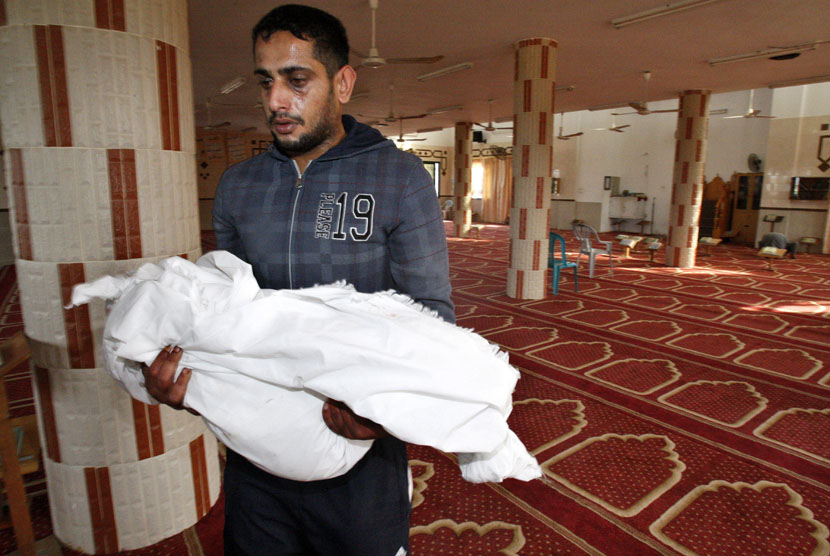  Yoused Abu Khoussa membawa jenazah putranya Iyad yang berusia satu setengah tahun untuk disalatkan di Kamp Pengungsi Bureij,Gaza, Ahada (18/11). (AP Photo/Adel Hana)