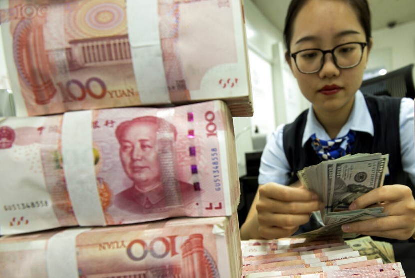 YUAN. Petugas bank menghitung dolar AS di samping tumpukan yuan Cina di Hai'an, Provinsi Jiangsu, China, Selasa (6/8). Nilai tukar yuan Cina merosot tajam atas dolar AS sebagai akibat dari perang dagang dengan Amerika Serikat.