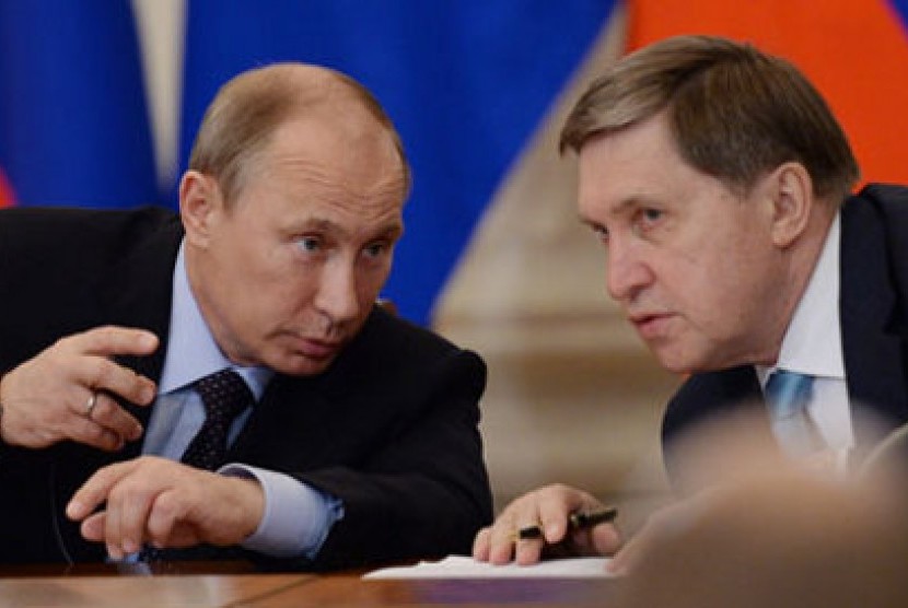 Yuri Ushakov (kanan) berbincang dengan Presiden Vladimir Putin