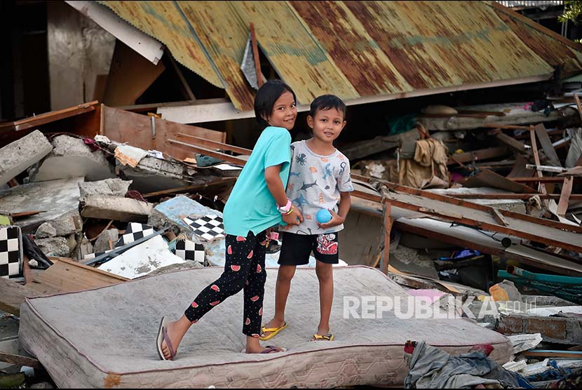 Zidan (kanan) dan Caca berpose di depan rumahnya yang rusak akibat gempa dan tsunami di Wani, Donggala, Sulawesi Tengah.