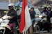   Bendera merah putih terlihat sebagai latar depan pemudik bersepeda motor yang melintasi jalur alternatif Cilamaya-Cikalong, Karawang, Jawa Barat, Jumat (17/8).(Aditya Pradana Putra/Republika)