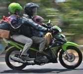 Pemudik sepeda motor dengan tiga penumpang melintas di Jalan Raya Mangkang Semarang, Jateng, Sabtu (27/11). Masih banyak pemudik sepada motor yang tidak menghiraukan larangan lebih dari dua orang. 