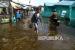 Sejumlah warga berjalan melintasi jalan yang terendam banjir rob di Pasar Kapuas Indah, Pontianak, Kalimantan Barat.