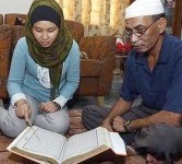 Sofe sedang membaca Alquran yang disaksikan orang tua temannya, Sha’ari Abdullah