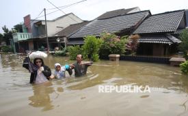 Warga menerobos banjir di Perumahan Ciledug Indah I, Tangerang, Banten, Selasa (8/7/2025). Banjir setinggi 50 cm - 200 cm yang merendam perumahan tersebut terjadi akibat meluapnya Kali Angke serta hujan deras. 