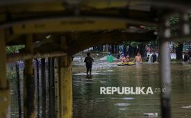 Warga berjalan menerobos banjir yang menggenangi jalan di kawasan Cempaka Putih, Jakarta, Ahad (18/1/2026).