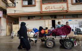 Pengungsi Palestina, termasuk perempuan dan anak-anak, membawa barang-barang mereka, setelah perintah evakuasi dikeluarkan oleh tentara Israel, di Rafah, 6 Mei 2024.