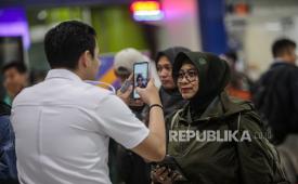 Petugas melayani calon penumpang yang mendaftarkan face recognition untuk memasuki gerbang menuju peron di Stasiun Gambir, Jakarta, Rabu (8/5/2024). 