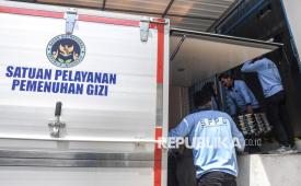 Pekerja memasukkan paket Makan Bergizi Gratis (MBG) ke dalam mobil untuk didistribusikan di Satuan Pelayanan Pemenuhan Gizi (SPPG).