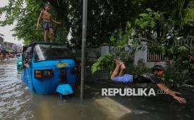 Warga beraktivitas saat banjir merendam kawasan permukiman di Pademangan Barat, Ancol, Jakarta Utara, Ahad (18/1/2026). Banjir setinggi sekitar 40-60 centimeter tersebut menggenangi permukiman di Pademangan Barat sejak pagi pukul 04.00 WIB yang disebabkan oleh intensitas hujan yang tinggi pada Sabtu (17/1) malam yang mengakibatkan luapan air dari kali Ancol, Kali Kwitang dan aliran drainase di kawasan tersebut.