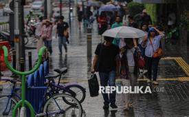 Warga menggunakan payung saat berjalan di kawasan Bundaran Hotel Indonesia, Jakarta, Jumat (2/1/2026). Penggunaan sunscreen tetap dibutuhkan meski sedang musim hujan.