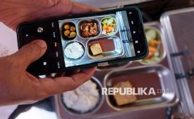 Seorang guru memotret hidangan makan bergizi gratis (MBG) saat waktu istirahat di SMP Negeri 1 Denpasar, Bali, Senin (19/1/2026).