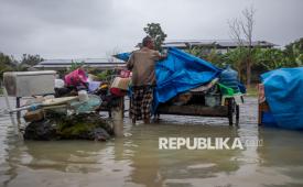 Seorang warga Mustakim (55) menutup sejumlah barang dengan terpal agar tidak kehujanan di tengah banjir yang menggenangi Desa Pilangwetan, Kecamatan Kebonagung,Kabupaten Demak, Jawa Tengah, Selasa (17/2/2026).    Menurut data sementara yang dihimpun Pusdalops BPBD Grobogan dan Demak hingga pukul 07:00 WIB, selain memutus akses jalur utama jalan Semarang-Purwodadi, banjir akibat dua titik tanggul Sungai Tuntang yang jebol itu berdampak pada total sekitar 3.924 jiwa di sejumlah desa wilayah Kabupaten Demak dan Grobogan. 
