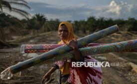 Siti Bayah (44) berjalan menyusuri jalan pedesaan antara Desa Babo dan Desa Rantau Bintang saat akan pulang ke Desa Jor, Aceh Tamiang, Aceh (21/12/2025). Siti dan Nurlela menempuh perjalanan sepanjang 40 kilometer dengan berjalan kaki untuk mencari kabar keluarganya  pascabanjir bandang di Desa Seumadam.