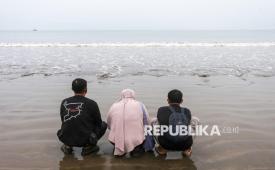 Istri dan anak jurnalis Merdeka.com yang hilang kontak, Arie Basuki, Yanti (tengah) dan Bintang (kanan) berdoa sebelum melakukan tabur bunga di bibir Pantai Kampung Pagedongan, Carita, Pandeglang, Banten, Jumat (18/9/2026). Keluarga, kerabat, beserta rekan-rekan jurnalis menggelar prosesi tabur bunga di sekitar titik awal keberangkatan lima jurnalis, dua awak kapal dan seorang pemandu untuk meliput erupsi Gunung Anak Krakatau setelah operasi pencarian oleh Tim SAR gabungan resmi dihentikan usai 10 hari pelaksanaan. 