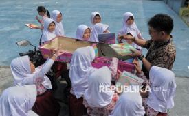 Pelajar membaca buku di perpustakaan keliling yang terparkir di Sekolah Dasar Negeri (SDN) Rawasari 01, Jakarta Pusat, Kamis (1/7/2024).