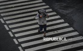 Warga melindungi kepalanya menggunakan tas saat hujan (ilustrasi). Perhimpunan dokter spesialis kulit dan kelamin Indonesia (Perdoski) menyampaikan potensi bahaya mikroplastik yang terkandung dalam air hujan terhadap kesehatan kulit.