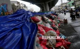 Pengendara motor melintas di samping tumpukan sampah yang ditutupi terpal di Ciputat, Tangerang Selatan, Banten, Selasa (16/12/2025). Pemerintah Kota Tangerang Selatan menutup tumpukan sampah menggunakan terpal sebagai bentuk penanganan sementara untuk mengurangi dampak bau selama masa penataan Tempat Pembuangan Akhir (TPA) Cipeucang yang membuat aktivitas pengangkutan sampah dihentikan sementara.