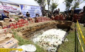 Petugas Satuan Polisi Pamong Praja dan Polisi melempar barang bukti ke dalam lubang pada pemusnahan minuman beralkohol di Lapangan Padebuolo, Kota Gorontalo, Gorontalo, Senin (29/12/2025). Pemerintah Kota Gorontalo bersama Polresta Gorontalo Kota melakukan pemusnahan 19.754 botol minuman beralkohol ilegal berbagai merk yang merupakan hasil penindakan tahun 2025. 