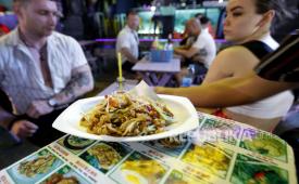  Staf restoran menyajikan pad Thai kepada wisatawan di Jalan Khao San di Bangkok, Thailand, 11 April 2023. Di restoran paling terkenal atau di sudut tersembunyi gang Bangkok, pad Thai telah menjadi surat pengantar Thailand ke dunia. Namun terlepas dari ketenarannya yang mendunia, konsep hidangan mi goreng yang ikonis ini masih baru. 