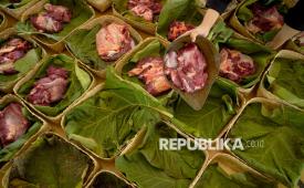 Warga membungkus daging kurban dengan daun jati di Masjid Margoyuwono, Kraton, Yogyakarta, Jumat (6/6/2025).  banyak orang masih menghadapi masalah yang sama yakni daging terasa alot saat dimasak.