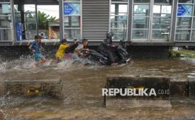 Anak-anak membantu pengendara mendorong motor saat melintasi jalan yang terendam banjir di Jalan Daan Mogot, Taman Kota, Jakarta, Jumat (23/1/2026). Ketika cuaca sudah kembali cerah, para pekerja dan siswa dimungkinkan untuk kembali beraktivitas seperti sedia kala. 