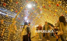 Warga menikmati suasana di sekitar aneka ornamen lampu hias dalam Jakarta Light Festival 2025 di kawasan Bundaran HI, Jakarta, Rabu (24/12/2025). Aneka ornamen lampu hias di sepanjang jalan protokol yang hadir mulai 23 hingga 27 Desember 2025 tersebut digelar dalam rangka memeriahkan perayaan Natal 2025 dan Tahun Baru 2026.