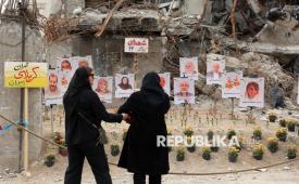 Warga melihat foto korban serangan udara AS-Israel yang dipajang di depan reruntuhan bangunan di Teheran, Iran, Senin (13/4/2026). Serangan AS-Israel ke Iran dilaporkan telah menewaskan lebih dari 1.300 orang. Dari jumlah korban itu, sedikitnya 210 anak dikabarkan tewas sejak dimulainya serangan gabungan Amerika Serikat dan Israel ke Iran. Iran dan AS gagal mencapai kesepakatan setelah perundingan perdamaian yang diadakan di Islamabad pada 11 April.