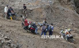 Warga mengangkat sepeda motor saat menyeberangi sungai wilayah Tenge Besi, Kecamatan Pintu Rime Gayo, Kabupaten Bener Meriah, Aceh, Sabtu (20/12/2025). Akses warga pejalan kaki masih harus melintasi jembatan darurat dari batang kayu dan kendaraan roda dua harus menyeberangi arus sungai saat debit air surut, sementara roda empat tidak dapat melintas, akibat jalan dan jembatan penghubung antara Bener Meriah menuju Takengon, Kabupaten Aceh Tengah putus diterjang banjir bandang pada Rabu (26/11). 