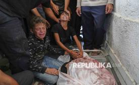 Dua anak Palestina menangisi jenazah ayahnya yang syahid saat menuju pusat distribusi bantuan, di kamar mayat Rumah Sakit Shifa di Kota Gaza, Rabu (18/6/2025). 