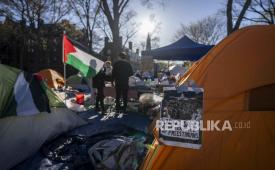 Mahasiswa yang memprotes perang di Gaza berdiri di samping bendera dan tenda Palestina di sebuah perkemahan di Harvard Yard, di Universitas Harvard di Cambridge, Mass, pada Kamis, (25/4/2024).