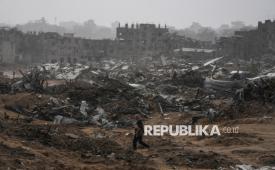 Seorang wanita Palestina berjalan di tengah hujan badai melewati bangunan yang hancur akibat serangan Israel di lingkungan Sheikh Radwan, Kota Gaza, Jumat (14/11/2025). Sebagian besar warga Gaza bergantung pada tenda-tenda usang untuk bertahan hidup. Kantor media pemerintah Gaza memperkirakan sekitar 93 persen tenda pengungsian sudah tidak layak huni, yakni sekitar 125.000 dari total 135.000 tenda. 