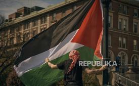 Seorang pengunjuk rasa memasang bendera Palestina di perkemahan pro-Palestina di Universitas Columbia, di New York, Ahad, (28/4/2024). 