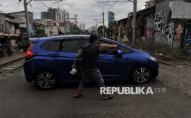 Suki (48) mengatur lalu lintas di perlintasan sebidang kereta kawasan Petamburan, Jakarta Pusat, Kamis (16/1/2025).