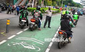 Polisi menertibkan pengendara motor yang melintas di jalur sepeda Jalan Jenderal Sudirman, Jakarta, Senin (28/4/2025).