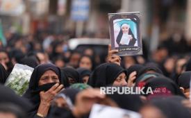 Warga memegang foto siswi yang menjadi korban serangan militer Israel-AS saat pemakaman massal untuk korban serangan sekolah perempuan di Minab, Iran, Selasa (3/3/2026). Sebanyak 165 siswi dan guru meninggal akibat serangan udara Israel-AS terhadap sekolah tersebut pada 28 Februari 2026. 